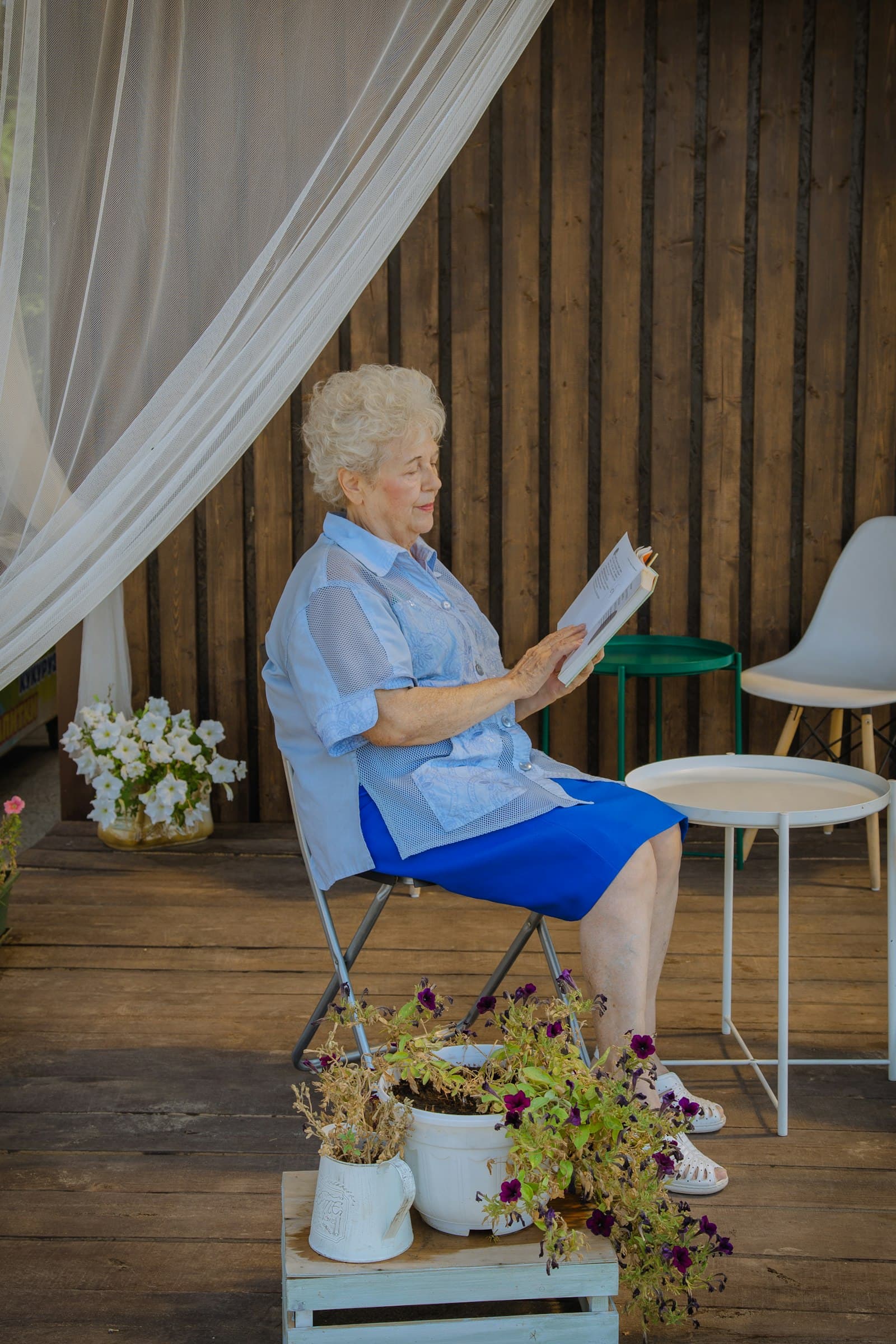 A woman in her 70s reading on a porch